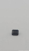 Emerald cut deep olive green tourmaline gemstone shown against a white background with focus on facets and clarity