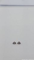 Front view of a pair of multicolored trillion cut sapphires on plain background.