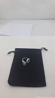 Ring displayed on a black velvet pouch, showing the full ring design and pouch.