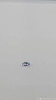 Oval cut aqua blue sapphire gemstone on a plain background shown from a distance.