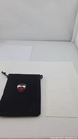 Ring with red and pink bi-color natural ruby set in sterling silver, displayed on black velvet pouch, shown from multiple angles.