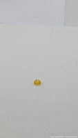 Photo of a single bright golden yellow oval cut sapphire gemstone on a white background.