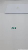 Six rectangular baguette cut Colombian emeralds with bright green color arranged on white background.