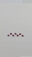 Eight pear-shaped deep red rubies arranged on white background