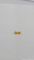 Pair of small oval cut golden canary yellow sapphires shown on a plain white background illustrating size and color.