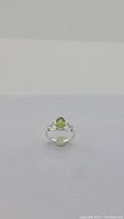 Front view of natural apple green peridot ring on sterling silver band, showing stone and decorative band accents.