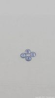 Four round faceted tanzanite gemstones arranged in a diamond shape on a light background.