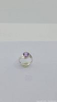 Front angled view of silver ring with round purple amethyst gemstone.