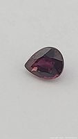 Close-up image of pear cut blood red ruby showing deep red color and facets.