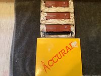 Three HO scale train boxcars packed in yellow Accurail labeled box, wrapped in white tissue paper.