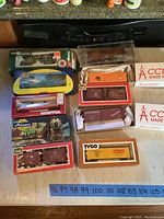 Overview of ten HO scale model train cars in original packaging from various brands placed on a countertop.