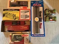 Overall group of boxed HO train cars, model kits, and track section showing lot contents.
