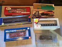 Top view of 6 HO scale model trains in packaging including Atlas, Walthers Mainline, and a NY Central bridge model car.