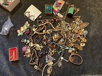 Top view of large assorted costume jewelry lot showing many items mixed together on dark cloth background