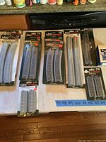 Photo showing sealed packages of Kato Unitrack curved and straight HO scale model train track pieces arranged on a table.