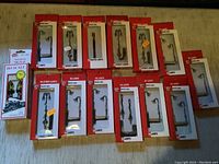 Top-down view of boxed HO scale street lamps and railroad signal on a wooden surface, showing variety of lamp shapes and packaging.