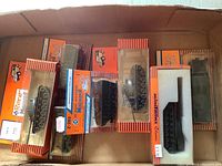 Top-down view of seven Rocco military mini tanks in original packaging showing orange and blue branded boxes with tanks inside plastic window.