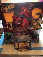 Spider-Man themed McDonald's Happy Meal display stand with figurines and spider web background.