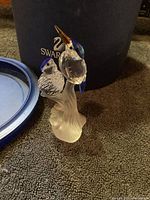 Photo of the Swarovski crystal hummingbird figurine with original box behind it on carpeted surface.