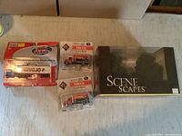 Wide photo of entire lot showing Scene Scapes box of trees, Boley International trucks in package and Mini-Metals Navajo tractor in package.