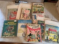 Photo showing 10 children's books including The Tin Woodman of Oz, The Merry Piper, Manni The Donkey, Cartes et Mappemondes, Le Petit Pioui, Come Play House, Guess Who Lives Here