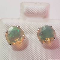 Front view of round faceted opal gemstones with play of color in 10K white gold prong settings.