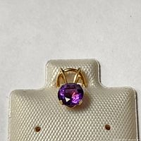 Front view of oval amethyst set in 14K yellow gold pendant on branded card.