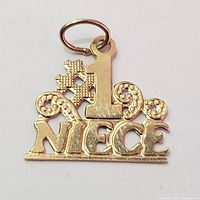 Front view of the 14K yellow gold pendant that reads '1 NIECE' with some decorative detailed swirls and textured design.
