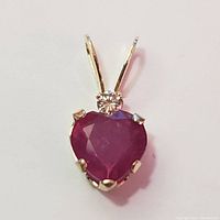 Front view of 14K yellow gold pendant with heart-shaped ruby and small round diamond.