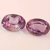 Top view of two oval shaped amethyst gemstones showing faceting and color