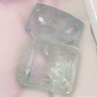 Close-up image of the aquamarine gemstone showing its faceted cut and rectangular cushion shape with light blue-green color and internal characteristics.