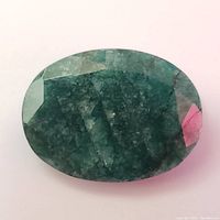 Close-up image of the faceted oval-shaped emerald gemstone showing its green color and natural inclusions