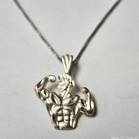 Close-up of silver muscle man pendant necklace showing flexed muscular figure on silver chain.
