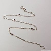 Full view of silver anklet showing chain length with four evenly spaced silver beads and clasp.