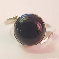 Close-up front view of silver ring with a round polished black onyx stone showing its glossy surface.