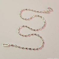 Silver bracelet laid out flat showing its full length and chain design.