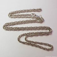 Full view of the silver rope chain necklace laid out on a flat surface showing the length and chain style.