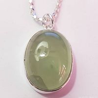 Front close-up photo of the oval chalcedony pendant set in silver, showing translucency and smooth surface of the stone.