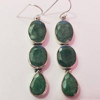 Front view of the pair of silver earrings showing three faceted green stones each with two oval and one pear shape.
