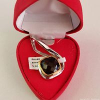 Pendant with faceted smokey quartz set in brass, shown in red velvet heart-shaped box.