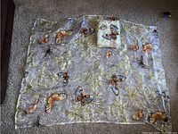 Full view of one transparent curtain featuring butterfly and floral designs spread out on floor.