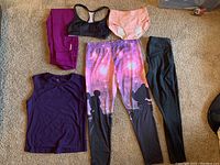 Full lot laid out on carpet, showing tops, leggings, panties, and sports bra in various colors and designs, including Disney Minnie Mouse leggings and Reebok leggings.