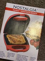 Photo of front of box showing Nostalgia MyMini Sandwich Maker with image of sandwich and tomatoes