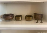 Four vessels and two incense holders displayed on a shelf, showing size and grouping.