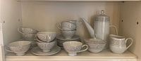 Shelf with the full Mikasa tea set showing all pieces including teapot, creamer, sugar bowl, cups, saucers, and bowls in the Winthrop pattern.