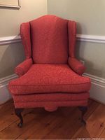Front view of the Queen Anne style occasional chair showing red patterned upholstery and wingback design.