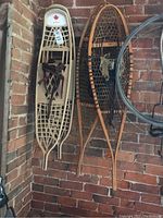 Two pairs of snowshoes hanging on brick wall, Victor Astro plastic frame and Faber wooden frame
