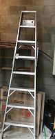 Full view showing the entire 8-foot tall aluminum step ladder leaning against a wall.
