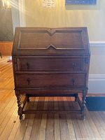 Front view of the wooden writing desk bureau showing slant front panel and two drawers with drop handles.