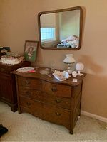 Photo of the antique wooden dresser with four drawers and decorative metal handles, with various items on top.